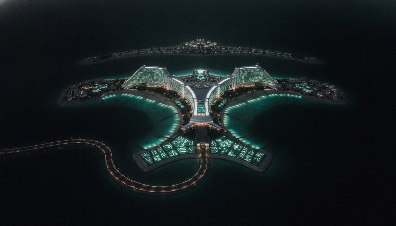 Night aerial of the island resort, lit like a broadcast stage against a black sea